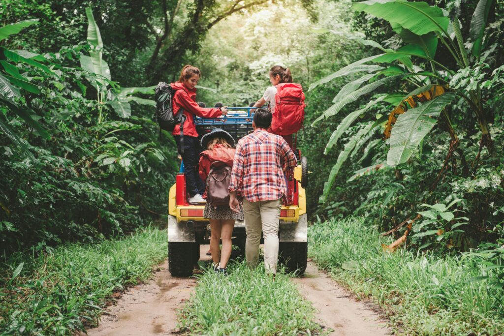 A picture of a group of students on a trail vehicle in what looks like engaging in sustainable tourism in a rainforest.