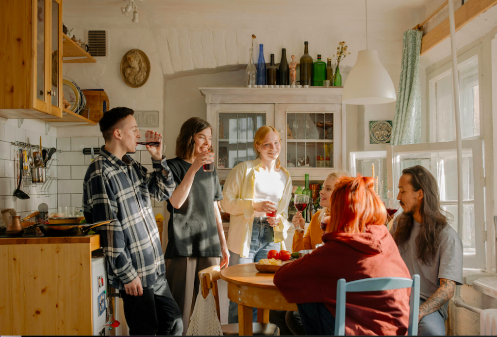 A picture of a group of young men and women networking over a drinks at a kitchen table