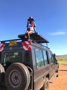 A picture of a lady atop an open-roof range rover tour vehicle in Tsavo East National Park